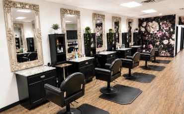 Modern salon with multiple styling stations and floral wallpaper.
