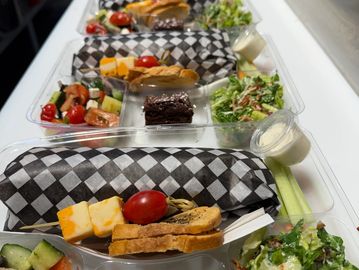 Lunch trays with sandwiches, salad, and brownies neatly arranged.