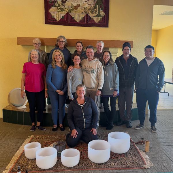 Group of wellness workshop participants gathered around crystal singing bowls during a breath traini