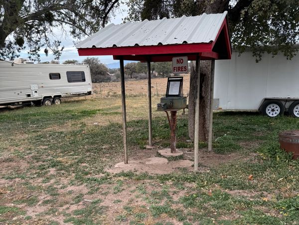 Outdoor water pump with a shelter and 'No Fires' sign nearby.