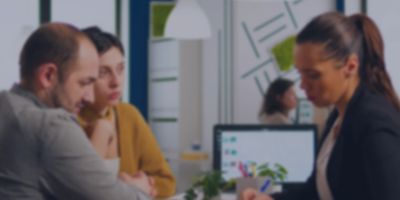 Three professionals engaged in a focused discussion in an office setting.