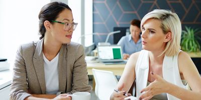 Two women having a serious discussion in a modern office.