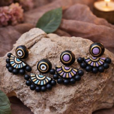 Set of colorful handcrafted earrings on a rock.