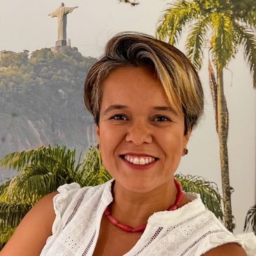 Smiling woman in white with Christ the Redeemer statue in background.