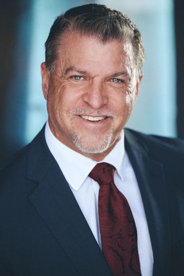 Professional man in suit and red tie smiling for headshot.