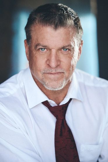 Middle-aged man in white shirt and red tie looking confidently at the camera.