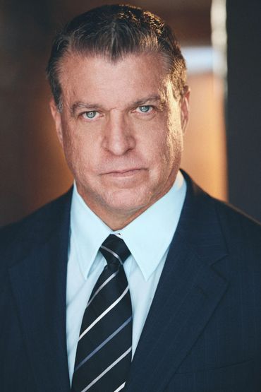 Serious man in suit and tie with piercing blue eyes.
