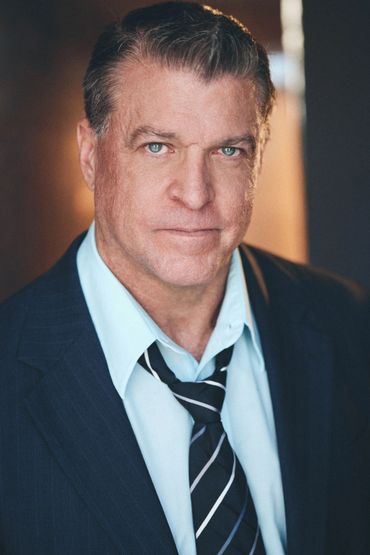 Confident man in suit with loosened tie looking directly at the camera.