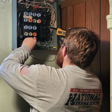 Electrician inspecting a circuit breaker panel in a basement.