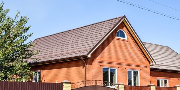 Modern house with brown tiled roof and wooden siding under clear sky.