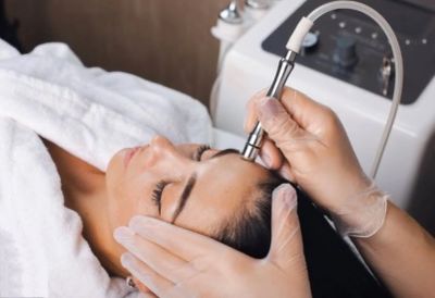 Person receiving facial treatment with a device.