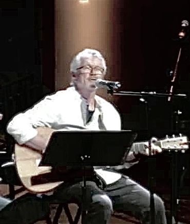 Older man playing guitar and singing.