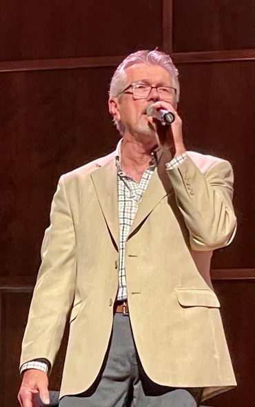 Man singing into a microphone on stage.