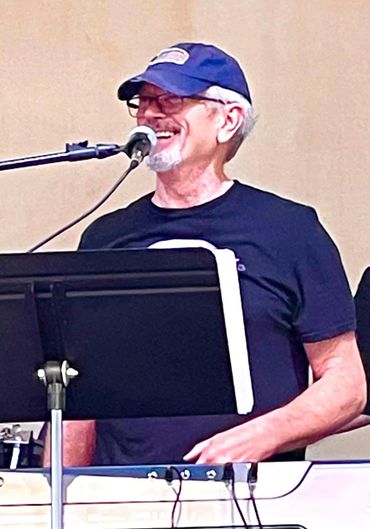 Smiling elderly man playing keyboard and singing.