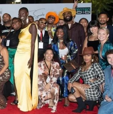 Group of people dressed stylishly posing on a red carpet.