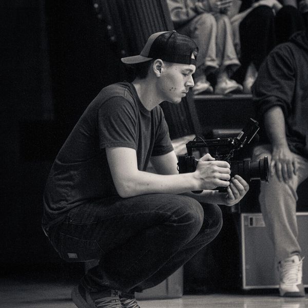 Young man crouching with a camera, focused on filming.
