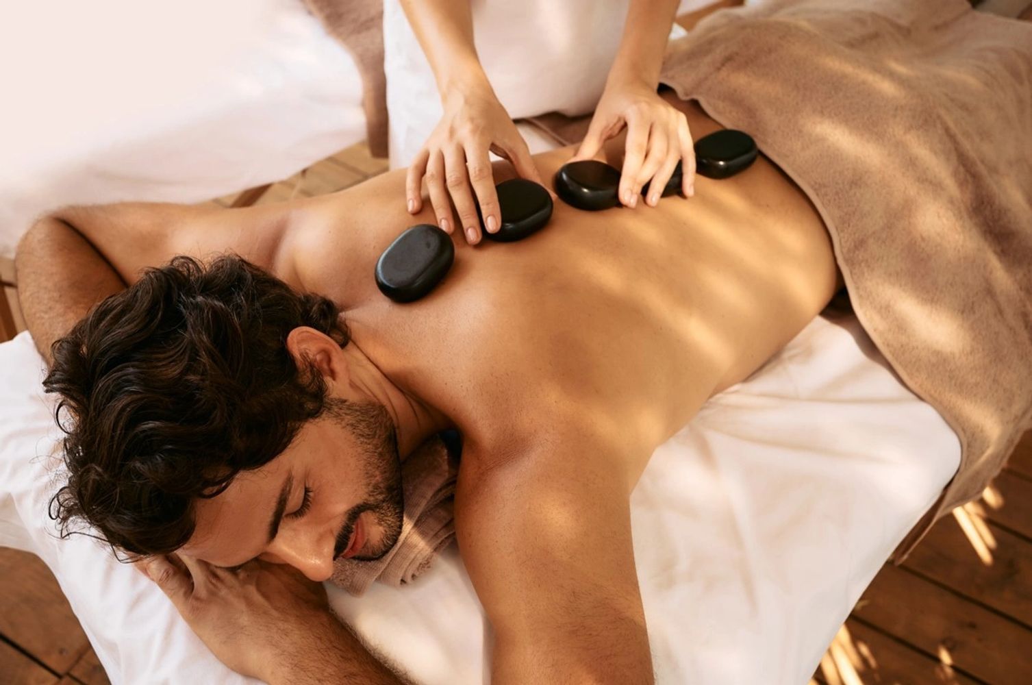 Man enjoying a hot stone massage on his back.