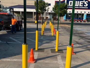 Parking lot with yellow poles and orange cones.