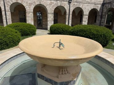 Circular stone fountain with a central water spout in a courtyard.