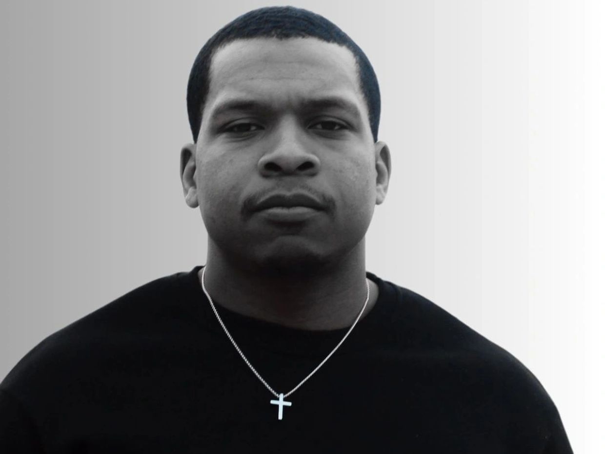 Portrait of a man wearing a cross necklace and black shirt.