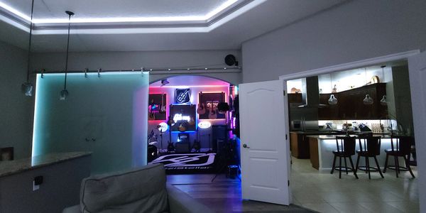 Modern living room with a neon-lit music studio and kitchen area.