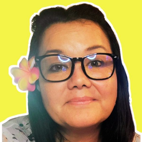 Woman with glasses and a flower in her hair against a yellow background.