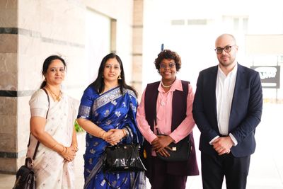 Four professionals posing indoors in formal attire.