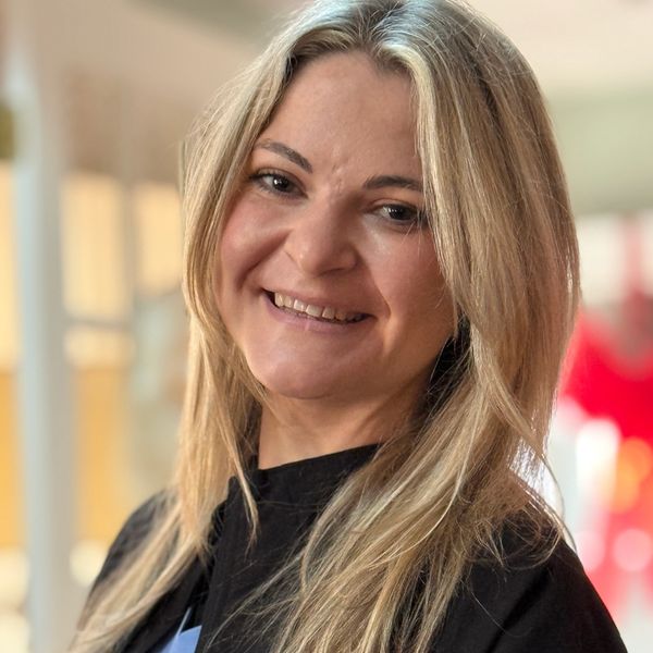 Smiling woman with blonde hair wearing a black top.