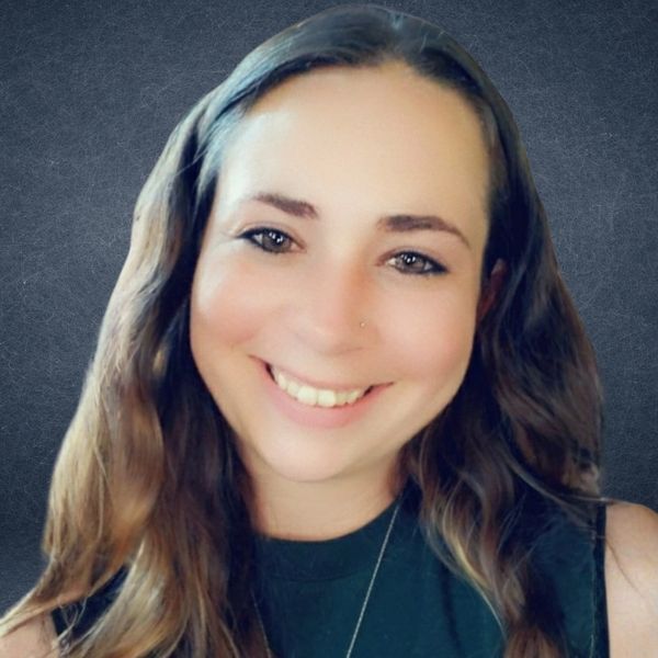 Smiling woman with long hair against a textured gray background.