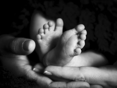 A baby's feet resting gently held by their parents.