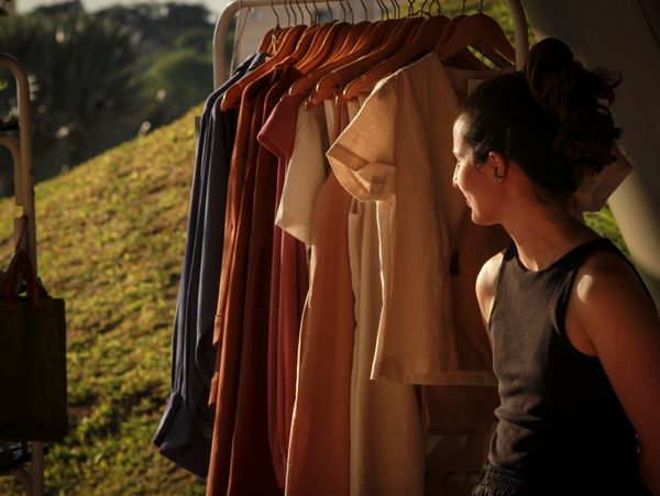 artista ao lado de sua arara de roupa curtindo um final de dia de sol de verão bem gostoso