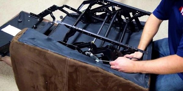 Person repairing or assembling the internal mechanism of a recliner chair.
