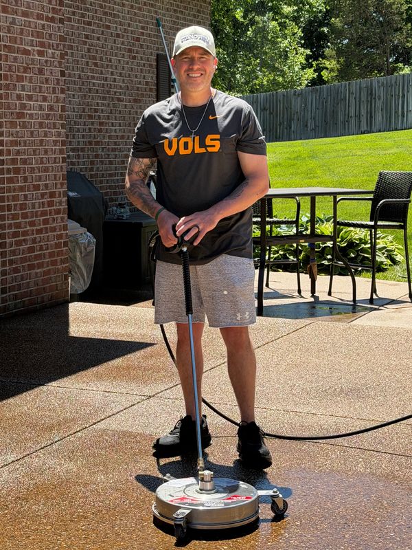 Man cleaning patio with a power washer.