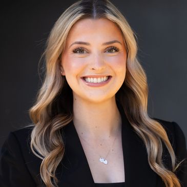 Smiling woman with long blonde hair against a dark background.