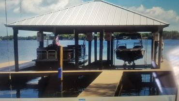 Covered dock with two boats on a calm lake under a blue sky.
