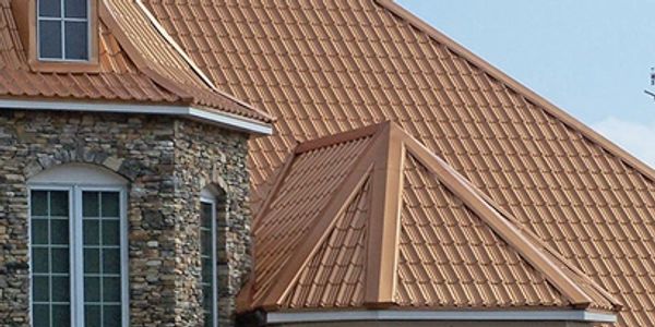 A house with a copper-colored metal roof and stone facade.