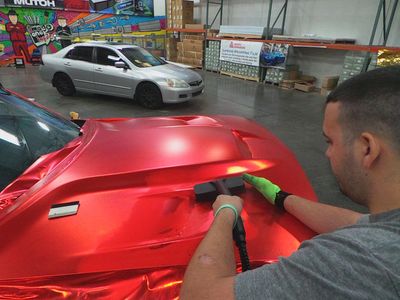 a man waxing a red color car