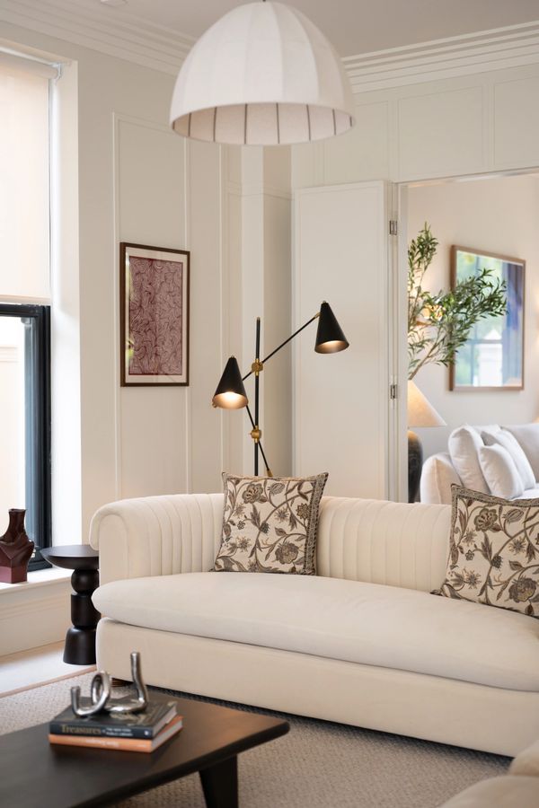 Elegant living room with cream sofa, patterned cushions, and modern lighting.