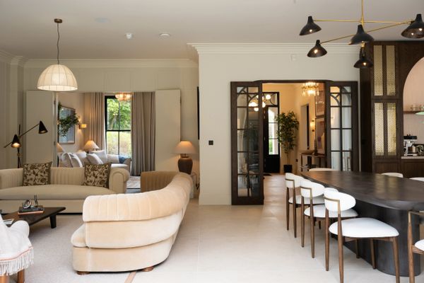Modern open living and dining area with beige tones and large windows.