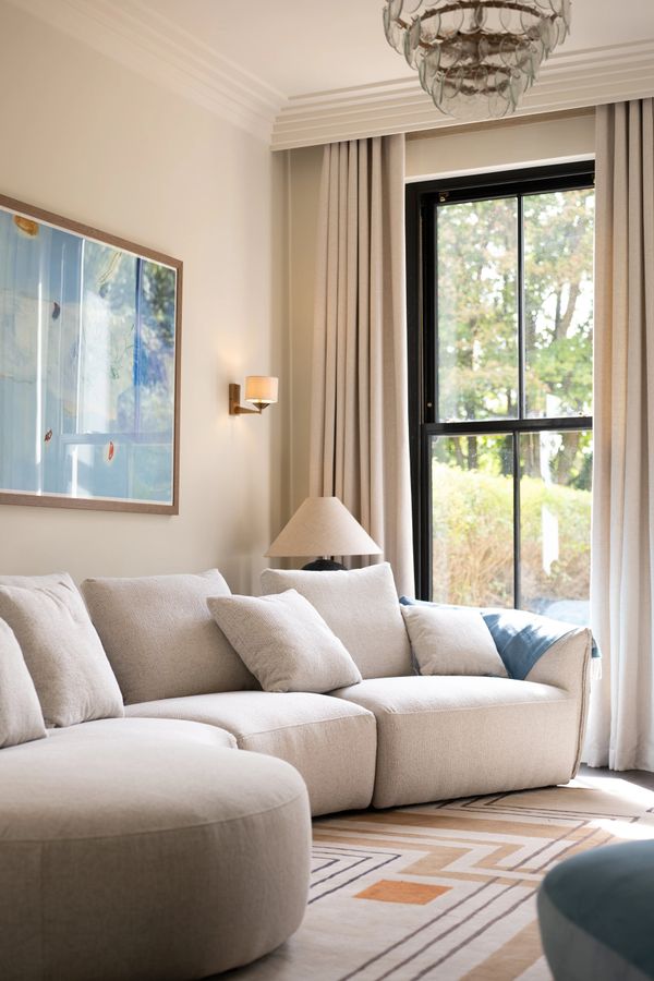 Bright living room with beige sectional sofa and large window.