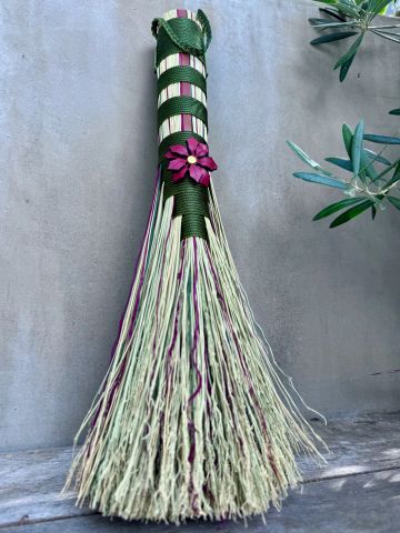 Decorative broom with green and purple accents and flower detail.