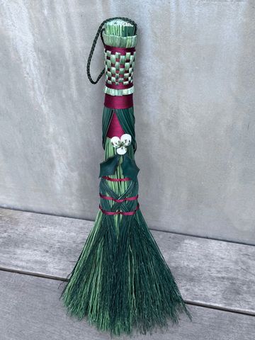 Decorative green and red broom with floral detail.