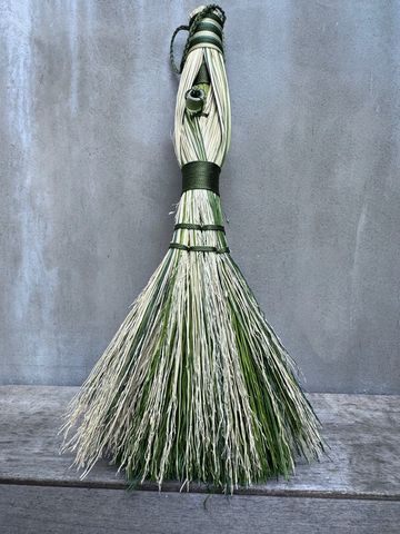 Handcrafted decorative broom with green accents.