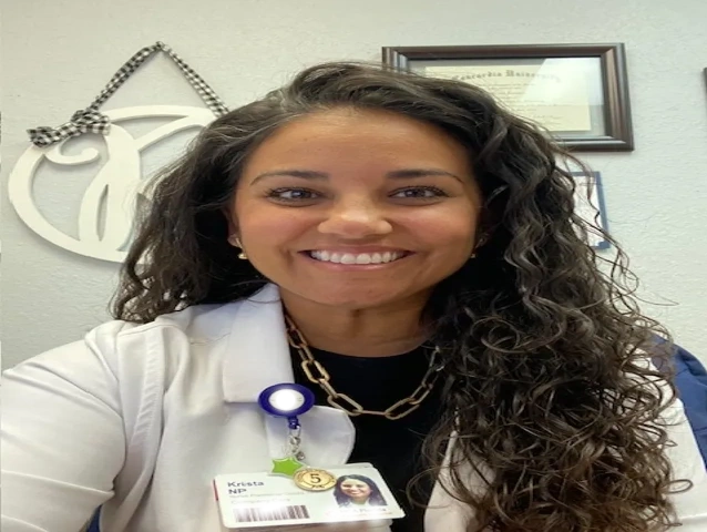Smiling healthcare professional in a white coat with curly hair.