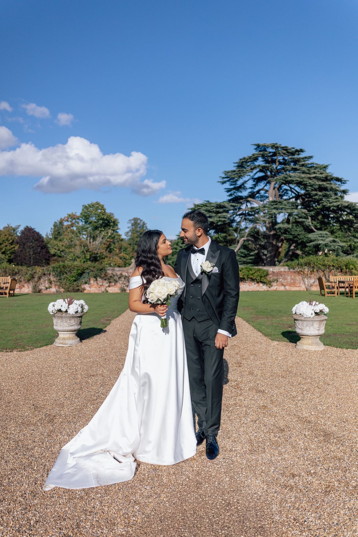 Bride and groom standing outdoors, gazing at each other on their wedding day.