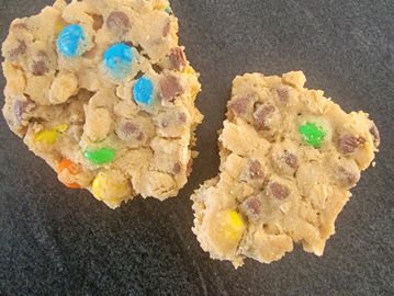 Two broken pieces of cookie with chocolate chips and colorful candy.