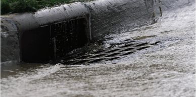 Image of street storm sewer inlet wiht water running into it. 