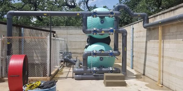 Commercial swimming pool filtration equipment and piping at an Interpool job site.