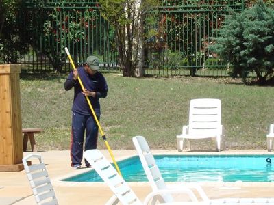 Person cleaning a backyard pool with a net.