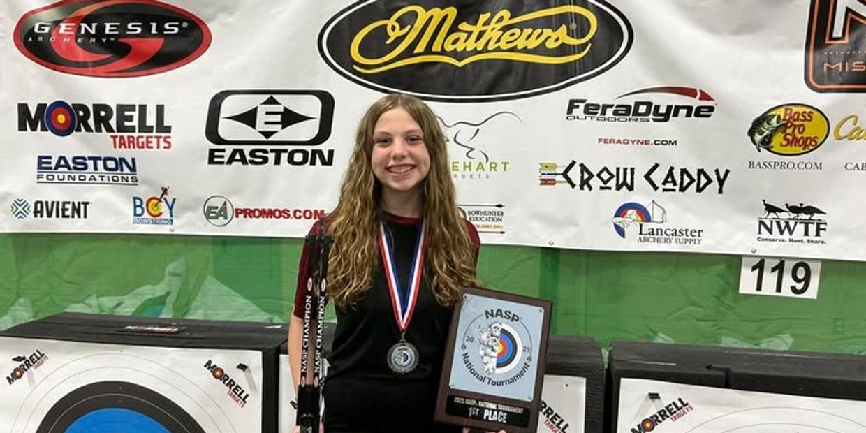 Young girl holding archery award plaque with medal.
